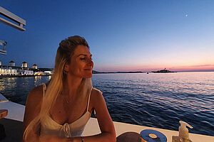 Sonnenuntergang mit einem Cocktail am Wasser und eine Yacht im Hintergrund