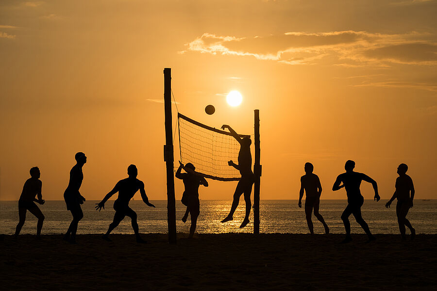 Silhouette einer Beachvolleyball-Gruppe am Strand bei Sonnenuntergang