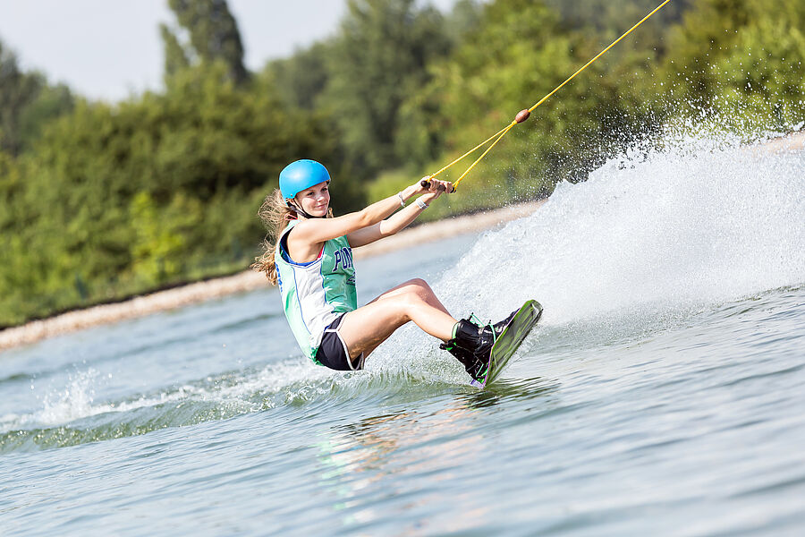 Junge Frau beim Wakeboarden auf dem Wasser
