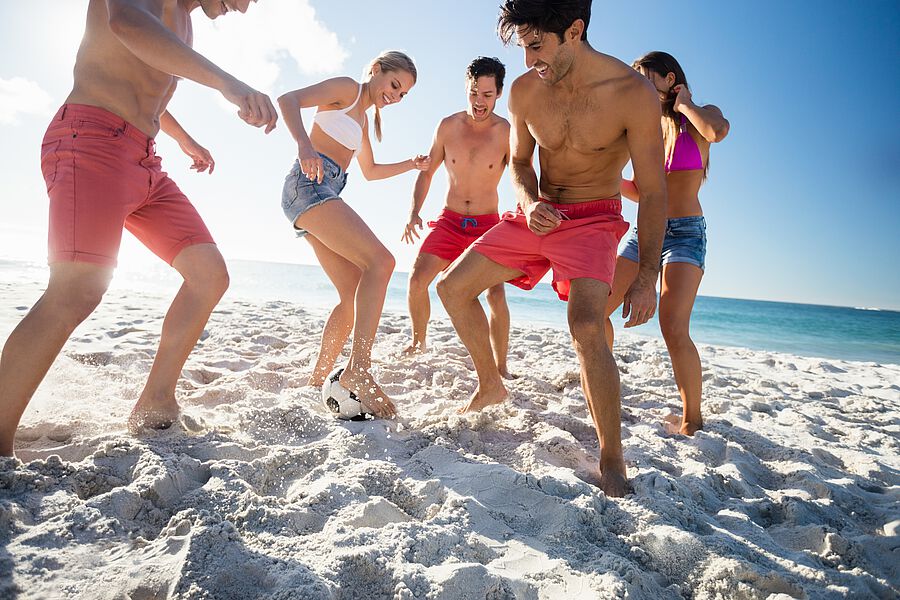 Gruppe spielt Fußball am Sandstrand
